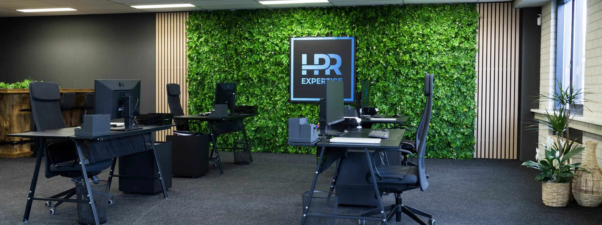 Kantoor van HPR Expertise in Spijkenisse met groene plantenwand, verlicht bedrijfslogo en werkplekken